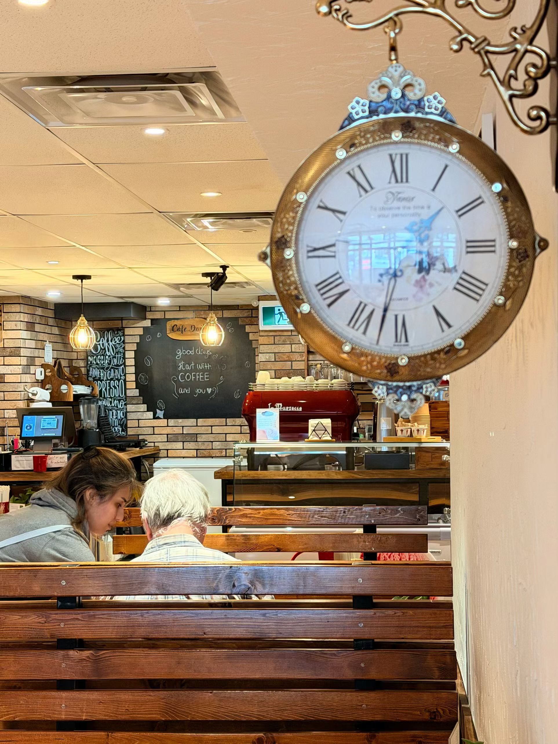 Inside Cafe Daily — vintage clock, brick walls, and cozy wooden tables